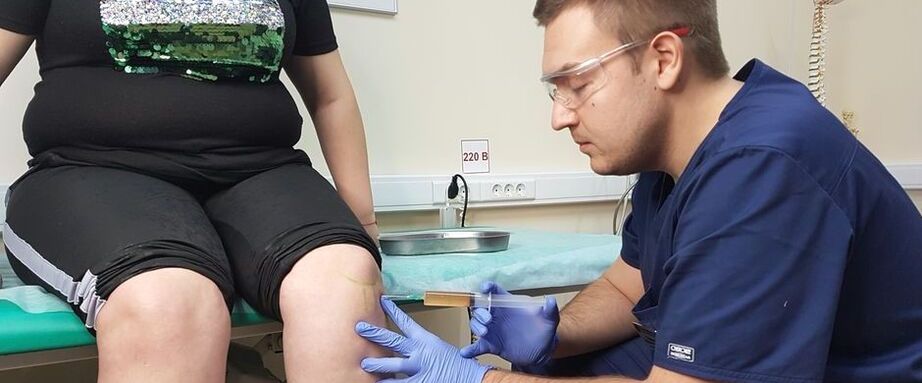 Ein Orthopäde führt bei Arthrose eine intraartikuläre Injektion in das Kniegelenk durch