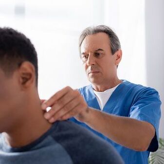 Ein Arzt führt eine diagnostische Untersuchung bei einem Patienten mit Nackenschmerzen durch.